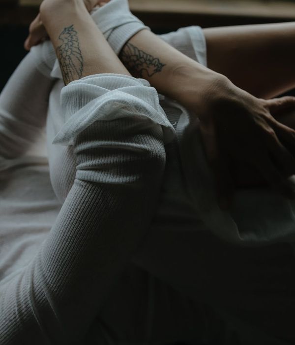 Woman performing a calm yoga pose in a dark, minimalist setting.